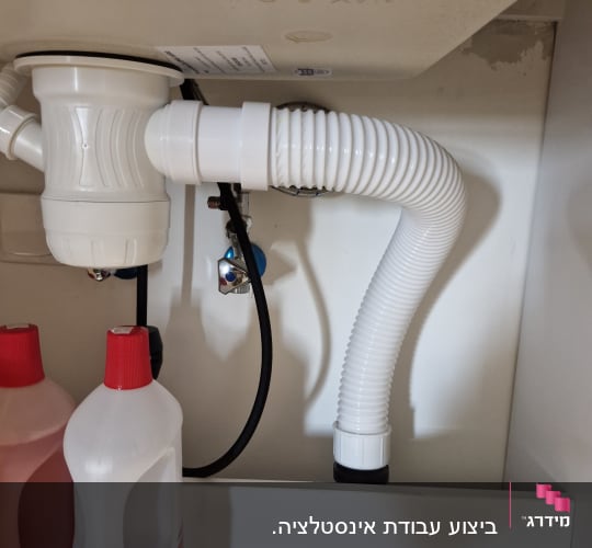 צינור ניקוז מתחת לכיור עם בקבוקי חומרי ניקוי